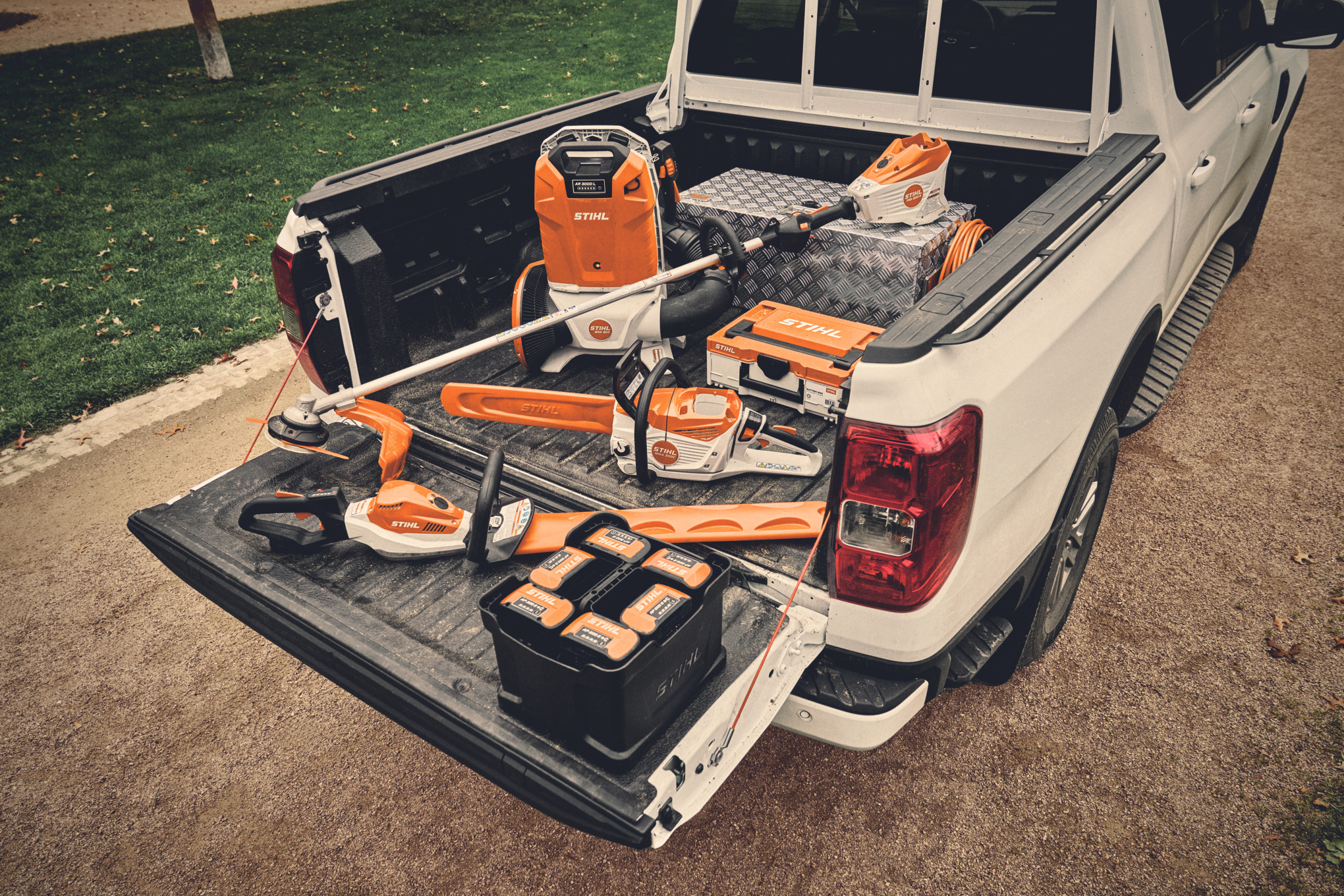 Diferentes máquinas de batería del sistema AP de STIHL y las baterías adecuadas en la superficie de carga de un vehículo