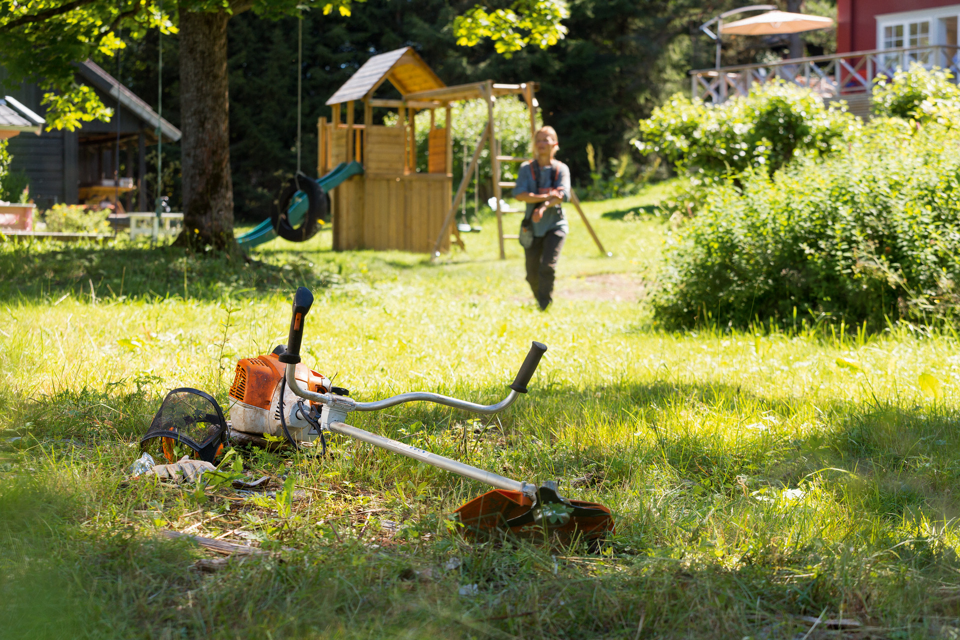 Una desbrozadora STIHL FS 240 sobre la hierba, en segundo plano un hombre se prepara para el mantenimiento