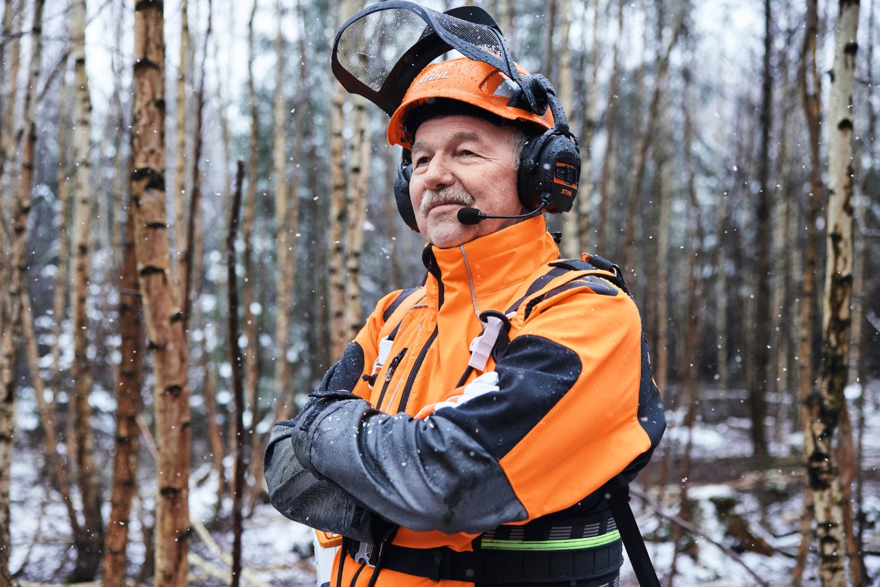 El maestro forestal Martin Nolte con ropa STIHL y los brazos cruzados en el bosque